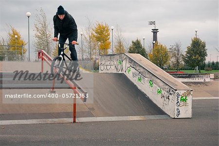 Biker doing crank slide grind trick down to red rail
