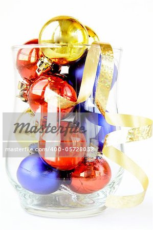 glass filled with colorful holiday ornaments and christmas decoration over white