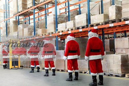 santa clauses in the line for the sacks of gifts in storehouse