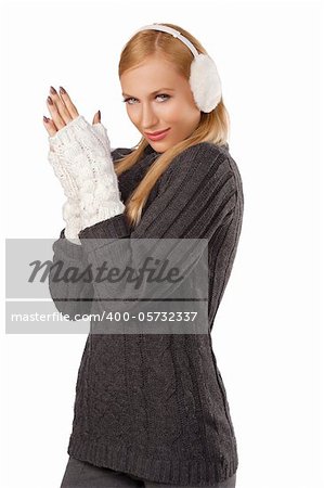 young pretty woman wearing white earmuffs and gray wool sweater be ready to go out in a cold winter day  standing  and feeling cold  against white background