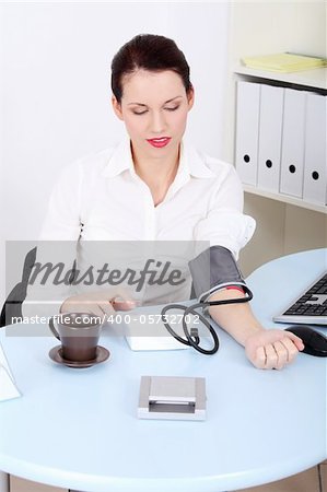Beautiful caucasian businesswoman measuring her blood pressure in the office.