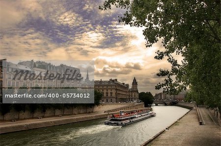 Touristic boat passing by Seine river along historical buildings in Paris, France