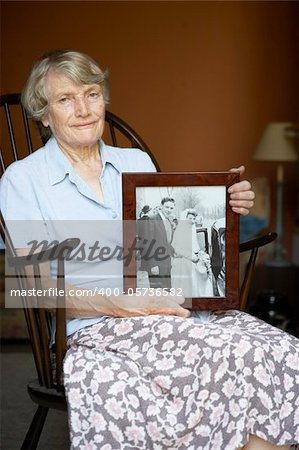 Senior Woman At Home Looking At Old Wedding Photo