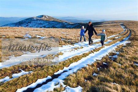 Family (mother with children) walk on autumn  mountain plateau with first winter snow