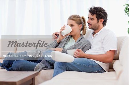 Young couple having a cup of tea in their living room