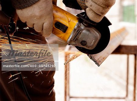 Worker hands cutting metal with sparks detail