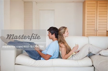Couple sitting back to back with a glass of wine in their living room