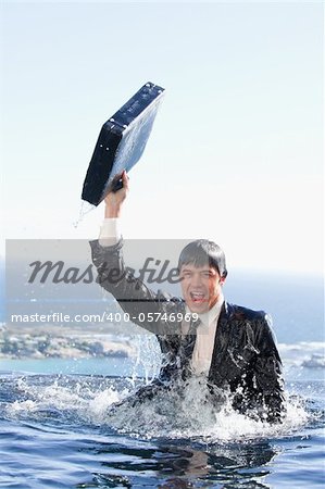 Portrait of a young businessman going out of the water with a briefcase in a swimming pool