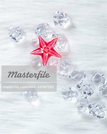 christmas red crystal star over ice cubes and white fur background