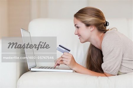 Side view of young woman on the sofa shopping online