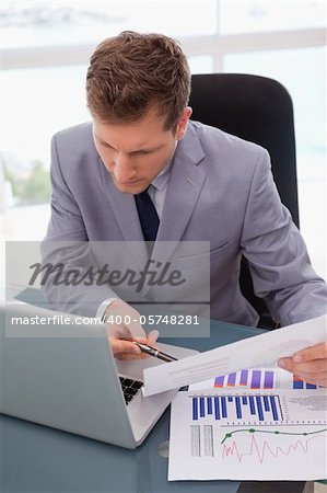 Businessman looking at his laptop while working on statistics