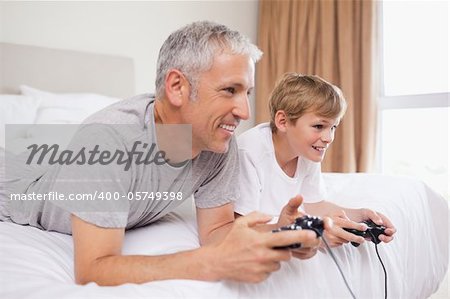Happy father and his son playing video games in a bedroom