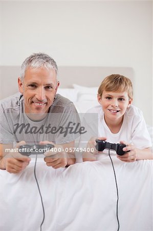 Portrait of a boy and his father playing video games in a bedroom