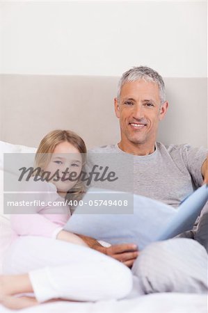 Portrait of a father reading a story to his daughter in a bedroom