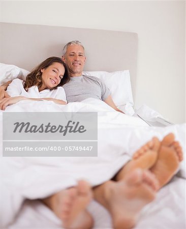 Portrait of a lovely couple lying on their bed while looking at the camera