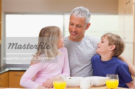 Smiling father with his children in the morning in a kitchen