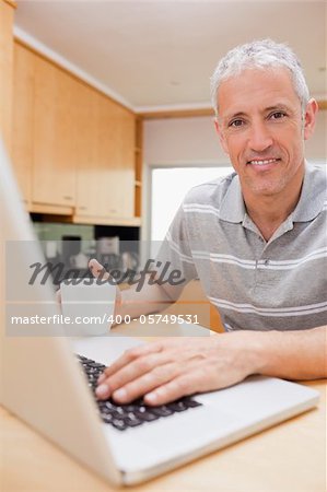 Portrait of a man using a notebook while drinking tea in a kitchen