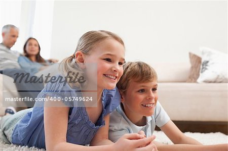 Siblings playing video games while their parents are watching in a living room