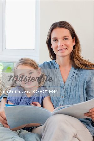 Portrait of a mother reading a book to her daughter in a living room
