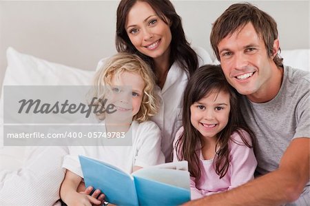 Happy family reading a book in a bedroom