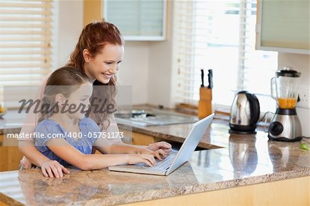 Mother and daughter together with laptop in the kitchen