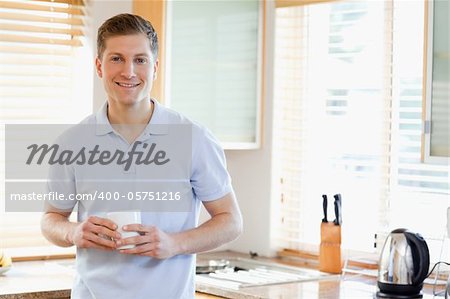 Man with white cup in the kitchen