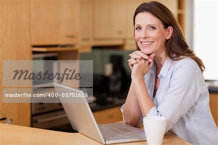 Smiling woman in the kitchen with her laptop