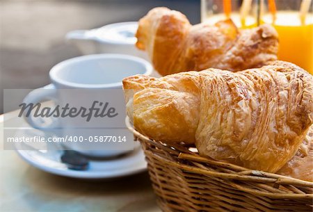 Breakfast with coffee and croissants in a basket on table