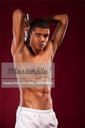 young fit man lifting dumbell. Shot in studio on a red background.