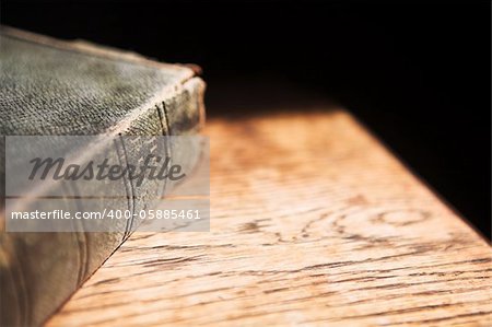 Leather covered old bible lying on a wooden table in a beam of sunlight Shallow Depth of field â?? Focus on Text â??Holy Bibleâ?