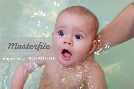 Small baby bathing in the bathroom on mother hands