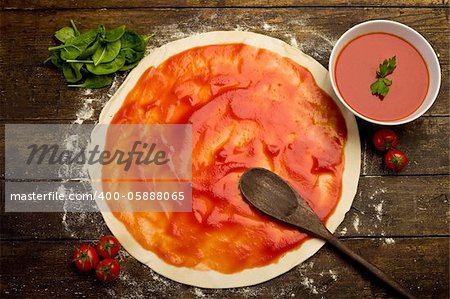 pizza dough with tomato sauce on rustical wooden table