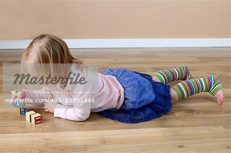 Little girl lying on her tummy building blocks