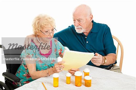 Disabled senior woman and her husband go over their medical and prescription drug bills.  Isolated on white.