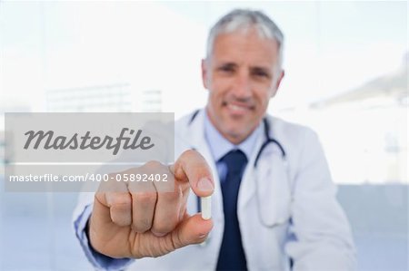 Doctor showing a pill in his office