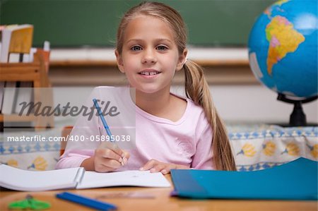 Smiling schoolgirl writing in a classroom
