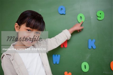 Schoolgirl pointing at a letter on a blackboard