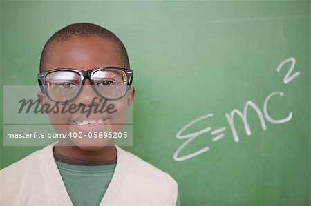 Schoolboy posing with the the mass-energy equivalence formula on a blackboard