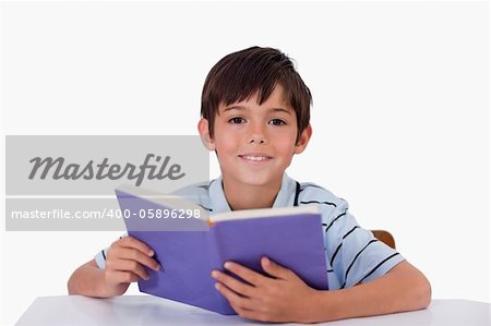 Happy boy reading a book against a white background