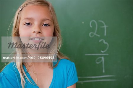 Little schoolgirl posing in front of a chalkboard