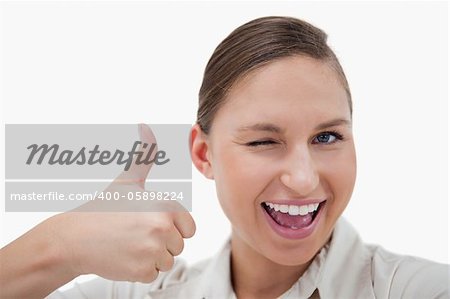 Businesswoman with the thumb up while winking against a white background