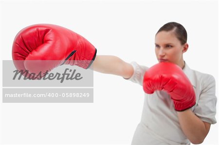 Businesswoman punching something with boxing gloves against a white background