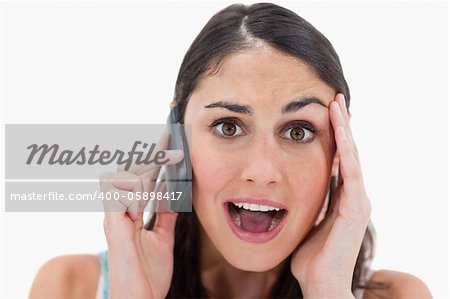 Shocked woman making a phone call against a white background