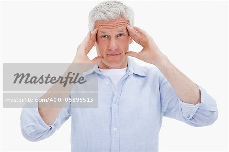 Mature man having a headache against a white background