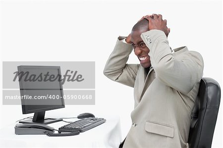 Furious businessman using a monitor against a white background