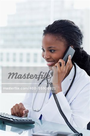 Portrait of a female doctor on the phone while using a computer in her office