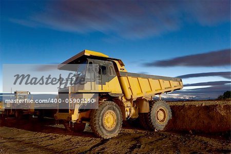 Huge auto-dump yellow mining truck night shot and excavator