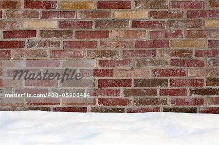 Modern wall of stone bricks and a ground covered with snow