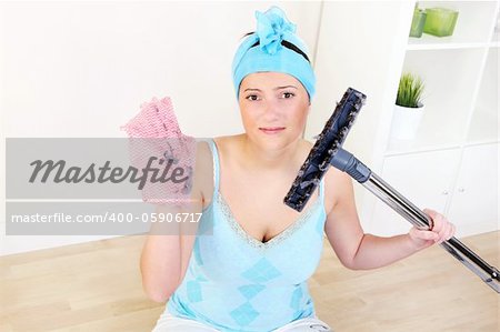 A picture of a tired unhappy housewife with a dirty rag in one hand and hoover in the other