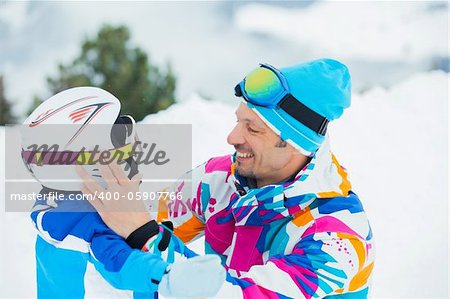 portrait closeup of happy and smiling father and son in ski goggles and a helmet